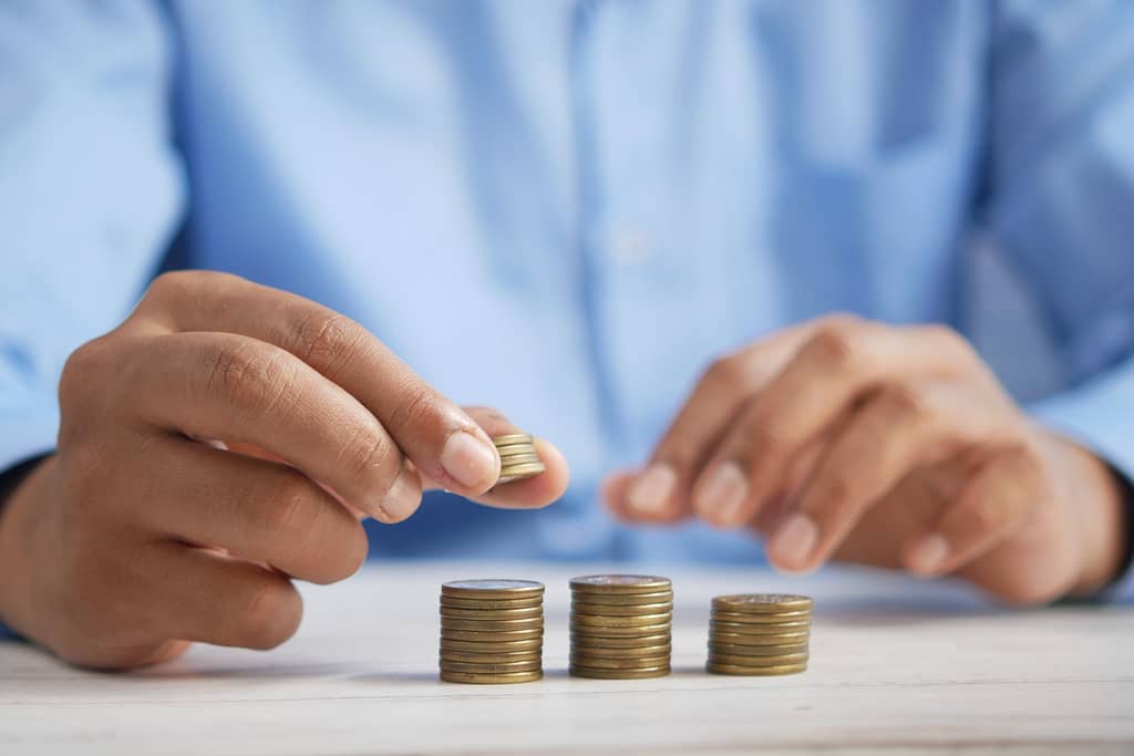 A man wearing a blue long-sleeve shirt, sitting and counting coins.