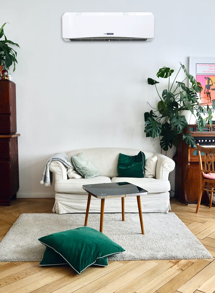 A green and wood-themed living room with a central table, a carpet, pillows, and a wall-mounted ductless mini-split system.